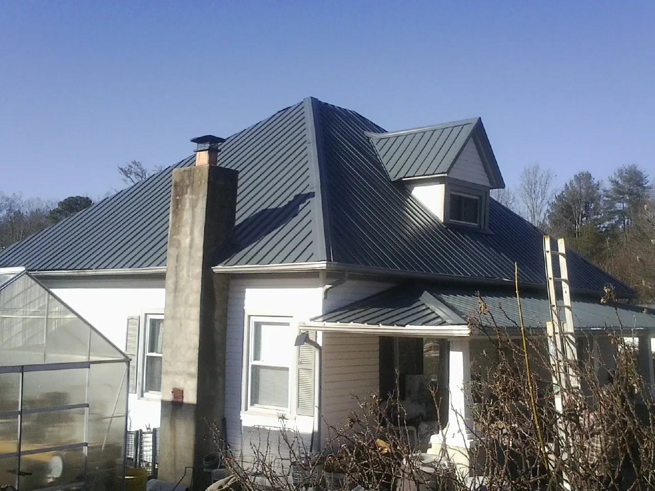 Dark blue standing seam metal roof on a white farmhouse with dormer — Slate & Tile Roof Repair by Roofing Brothers in Elk Falls