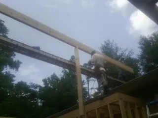 Carpenter setting a ridge beam over a new addition frame — Ice Dam Removal by Roofing Brothers in Elk Falls