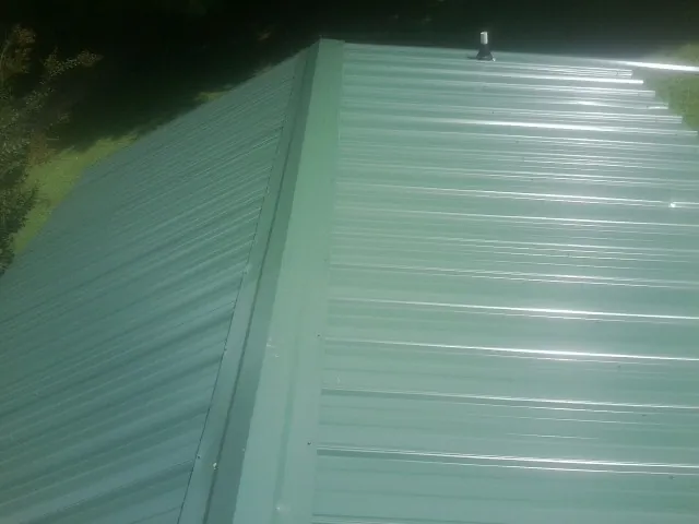 New green metal panels meeting at the ridge of a roof — Flat Roof Repair work by our crew in Elk Falls