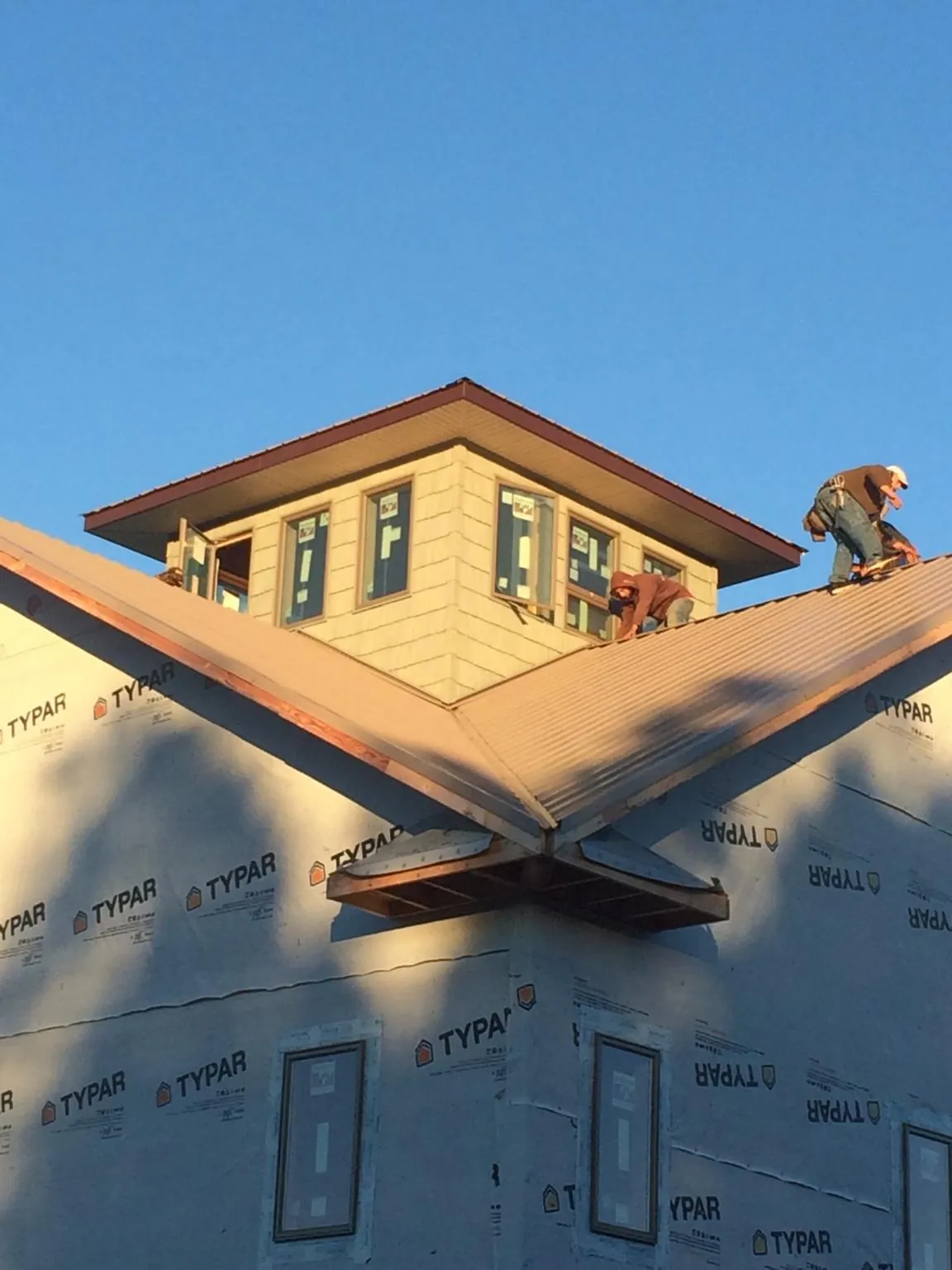Roofers working around a rooftop cupola on a new metal roof at sunset — Roof Waterproofing in Elk Falls by Roofing Brothers